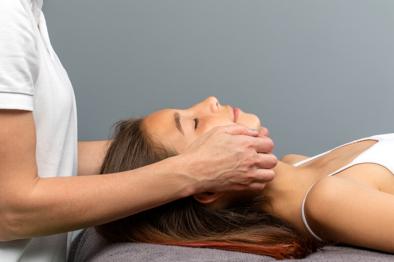 woman lying down while physiotherapist assesses jaw